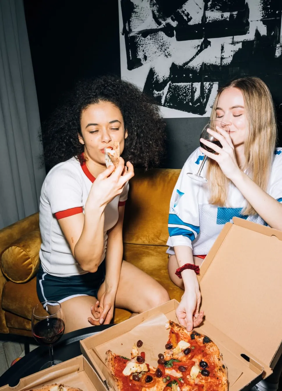 Two girls eating pizza at a home party